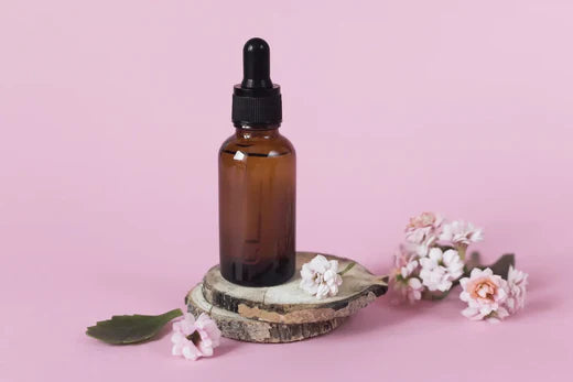 DIY Face Serum recipe in essential oil amber bottle with pink and flowers