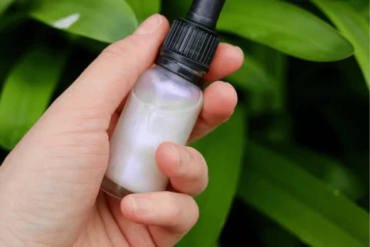 Spring luminescence face oil Go Native NZ skincare recipe held in hand in dropper bottle by green leaves