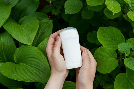 Go Native NZ Body care recipe Vegan Deodorant in tube held buy hands in front of lush green leaves