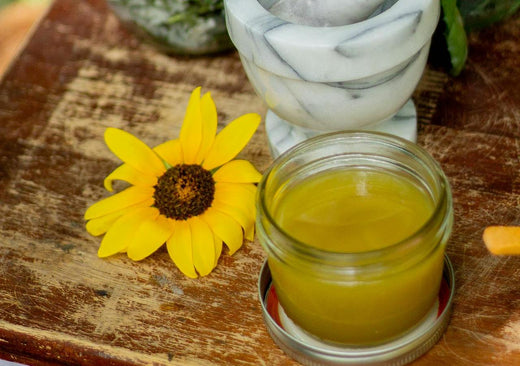 homemade yellow Bug Off Balm in glass jar on wood tray