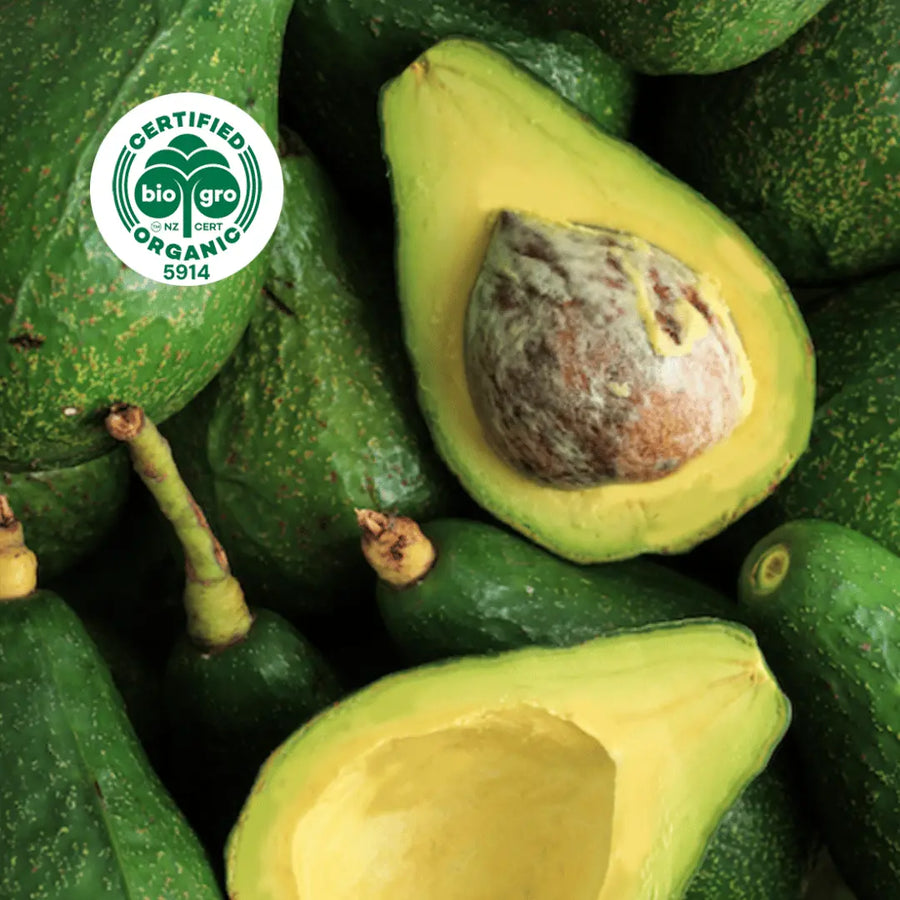 Green avocados whole and cut open with bio gro logo in the top left corner to verify Go Native New Zealand's organic certification for organic avocado carrier oil