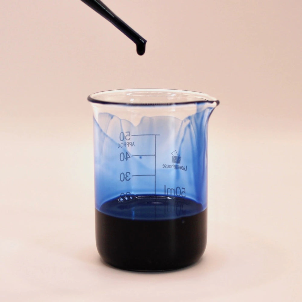 Stunning deep blue colour of german chamomile essential oil in a clear glass beaker with a pipette dropping more from above