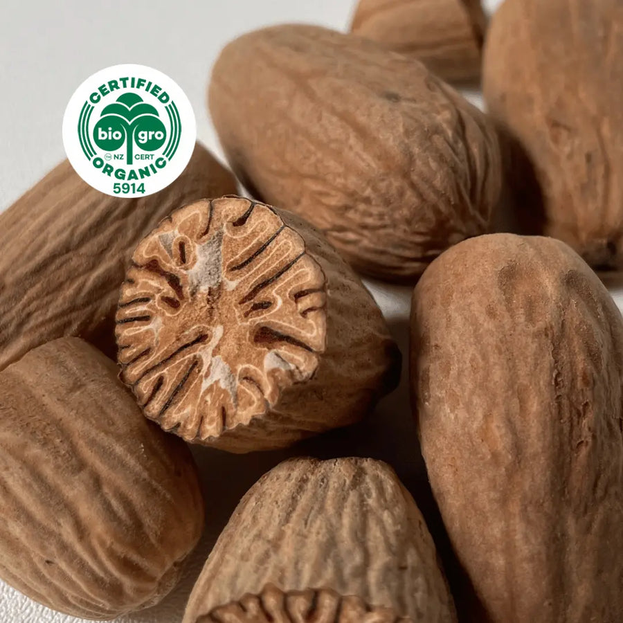 Nuts with one in half show filigree wood pattern Raw ingredients to make Nutmeg essential oil with Go Native NZ Biogro certified organic icon