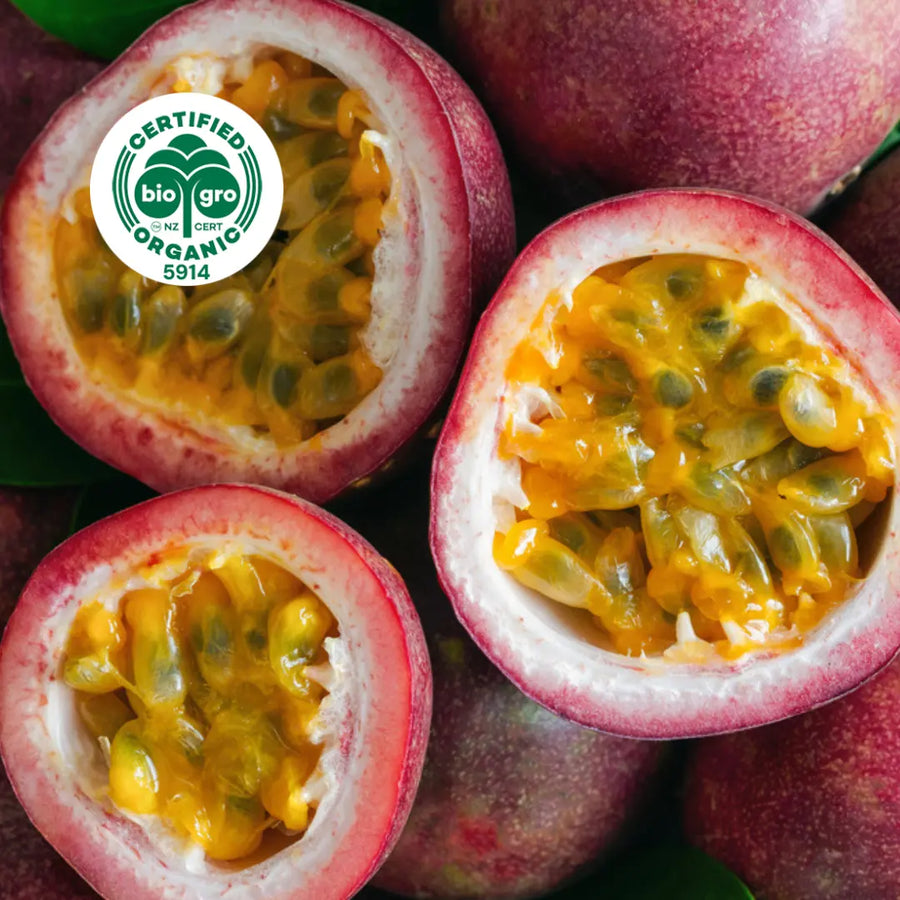 close up of three halved passionfruits revealing purple skin and yellow and black seed inside with bio gro Certified Organic icon to verify Go Native New Zealand's organic certification for passionfruit seed carrier oil