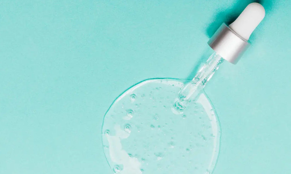 Dropper with clear liquid on a light blue background