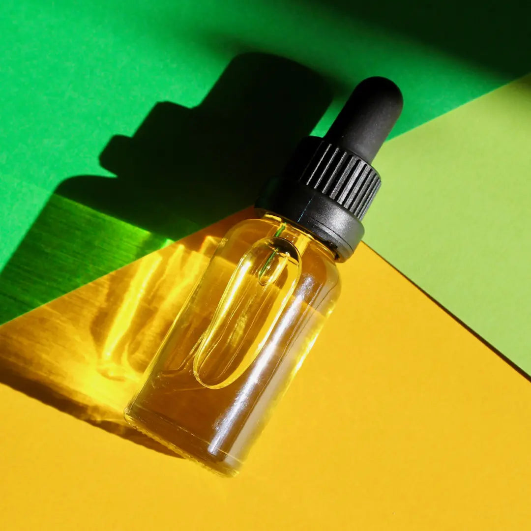 Yellow dropper bottle with black cap on a green and yellow geometric background